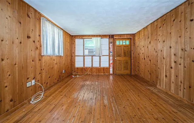a view of an empty room with wooden floor and a window