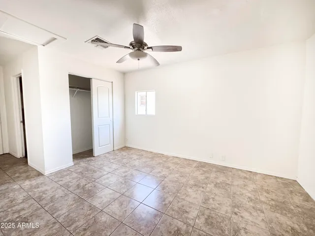 an empty room with windows and fan