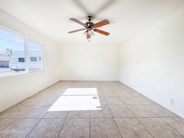 an empty room with windows and fan