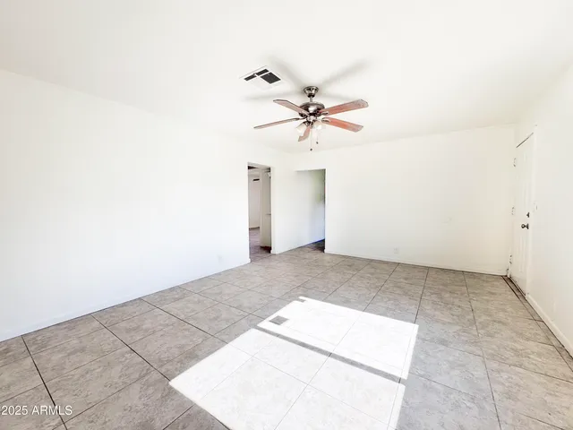an empty room with a chandelier fan and windows