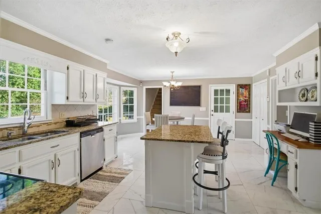a kitchen with granite countertop cabinets a stove a dining table and chairs