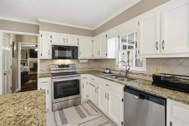 a kitchen with stainless steel appliances granite countertop a stove a sink and a microwave