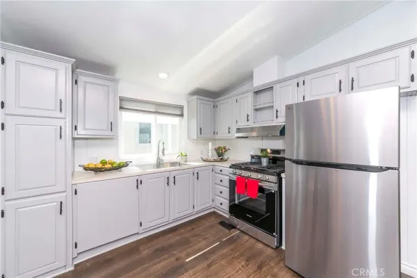 a kitchen with refrigerator a white cabinets and wooden floor