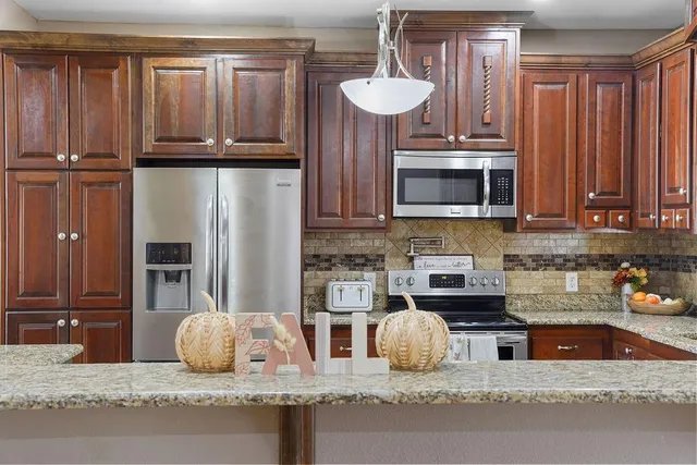 a kitchen with stainless steel appliances granite countertop a refrigerator a stove a sink and dishwasher