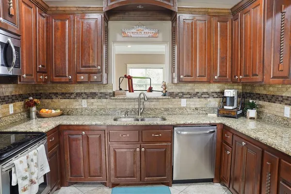 a kitchen with granite countertop wooden cabinets a sink and dishwasher