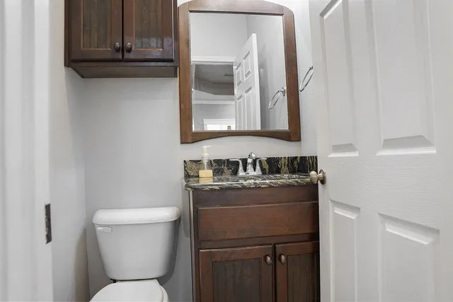 a bathroom with a granite countertop toilet sink and mirror