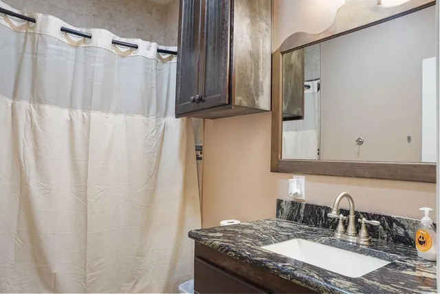a bathroom with a granite countertop sink and a mirror