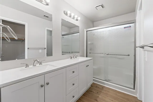 a bathroom with a double vanity sink mirror and shower
