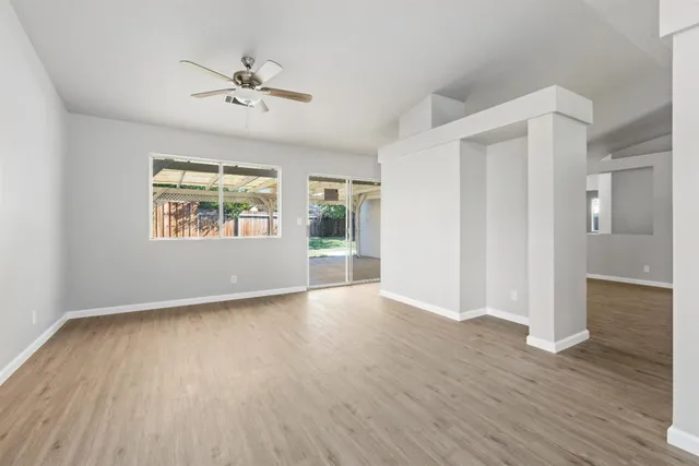 an empty room with wooden floor chandelier and windows