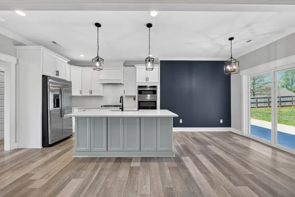 a kitchen with kitchen island a counter top space cabinets stainless steel appliances and a ceiling fan