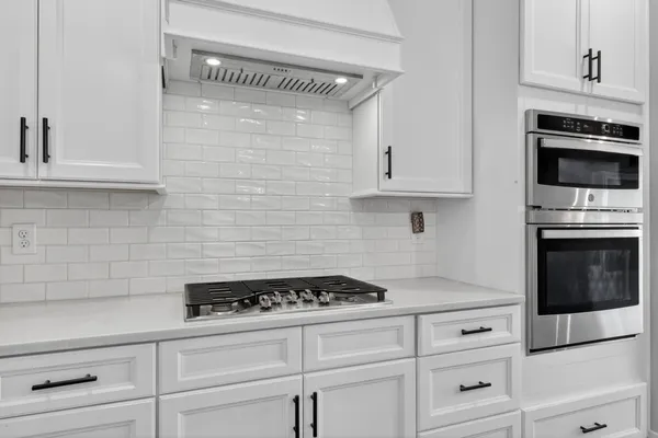 a kitchen with stainless steel appliances a stove a sink island and a refrigerator with wooden floor