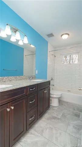 a spacious bathroom with a granite countertop sink a toilet and a bathtub