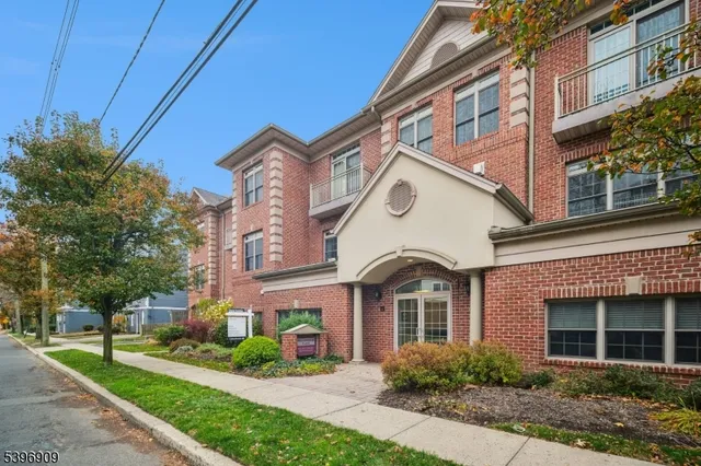 a living room with stainless steel appliances furniture a rug and a refrigerator