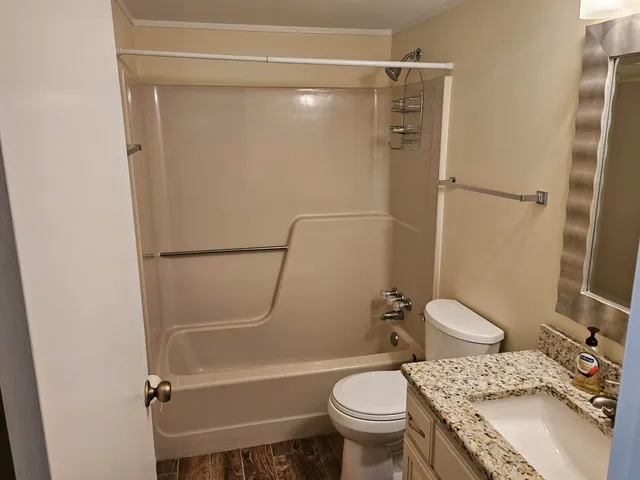 a bathroom with a granite countertop bathtub shower sink vanity and toilet
