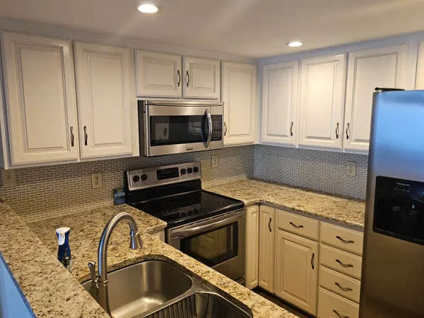 a kitchen with granite countertop white cabinets and black appliances