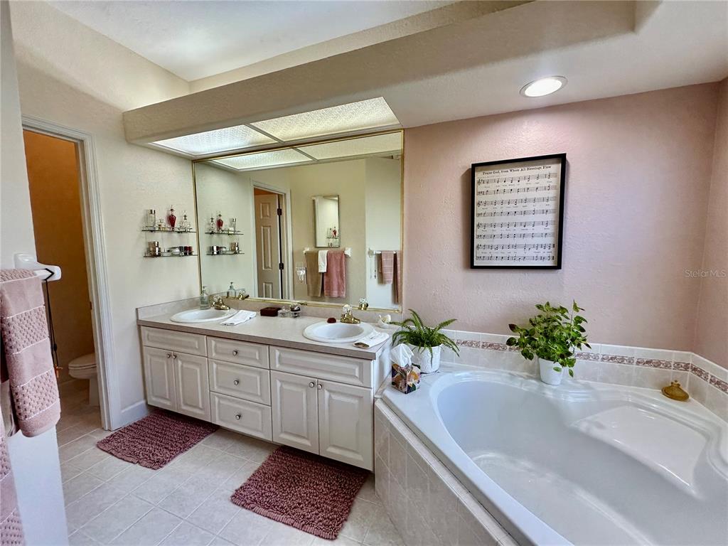357 Ruby Lake Loop Winter Haven, FL 33884 - Photo 17 of 31 a bathroom with a granite countertop sink a large mirror and a bathtub