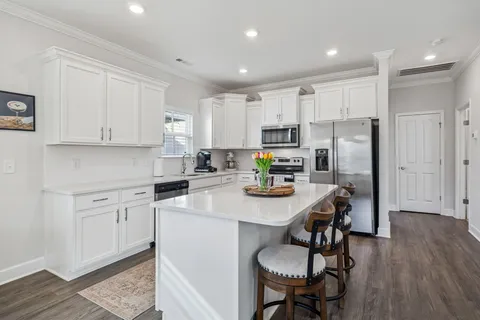 a kitchen with a refrigerator a stove a sink dishwasher and white cabinets with wooden floor