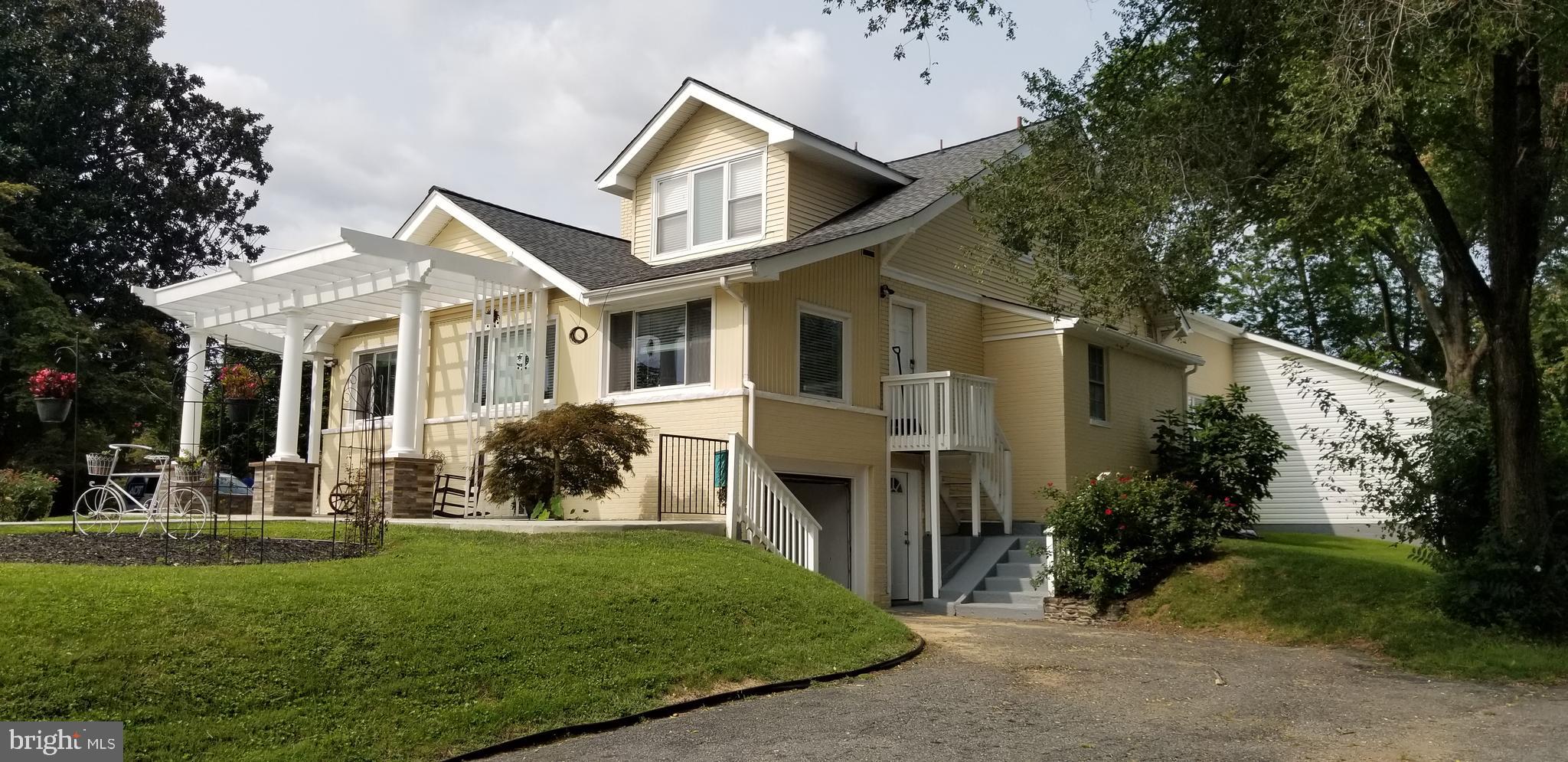 a view of a white house next to a yard with big trees