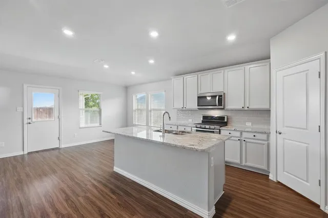 a kitchen with stainless steel appliances granite countertop a stove a sink and a refrigerator