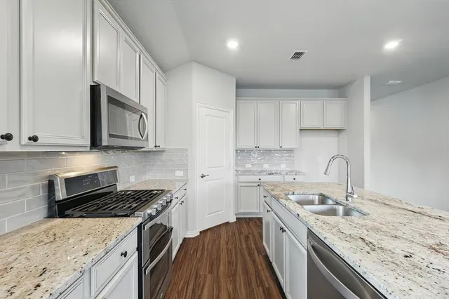 a kitchen with granite countertop stainless steel appliances cabinets a sink and a counter space