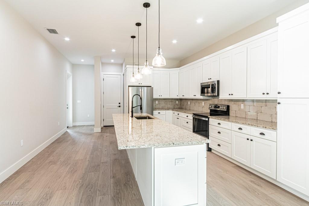 3552 Hibiscus Avenue Naples, FL 34104 - Photo 11 of 34 a large kitchen with white cabinets stainless steel appliances and a center island
