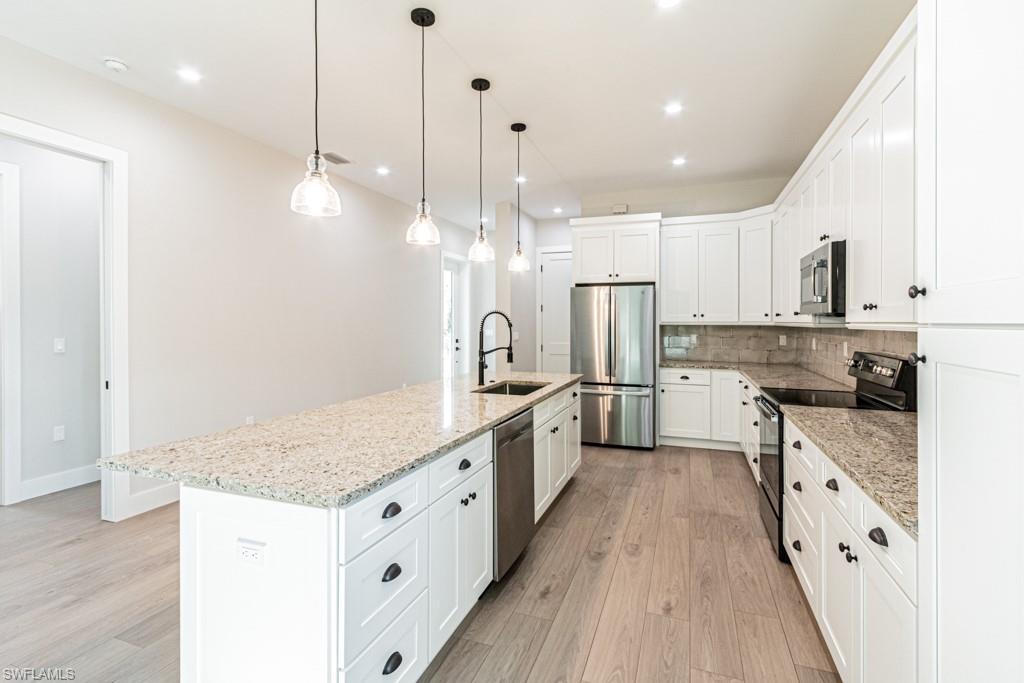 3552 Hibiscus Avenue Naples, FL 34104 - Photo 12 of 34 a kitchen with kitchen island granite countertop a sink a counter top stainless steel appliances and cabinets