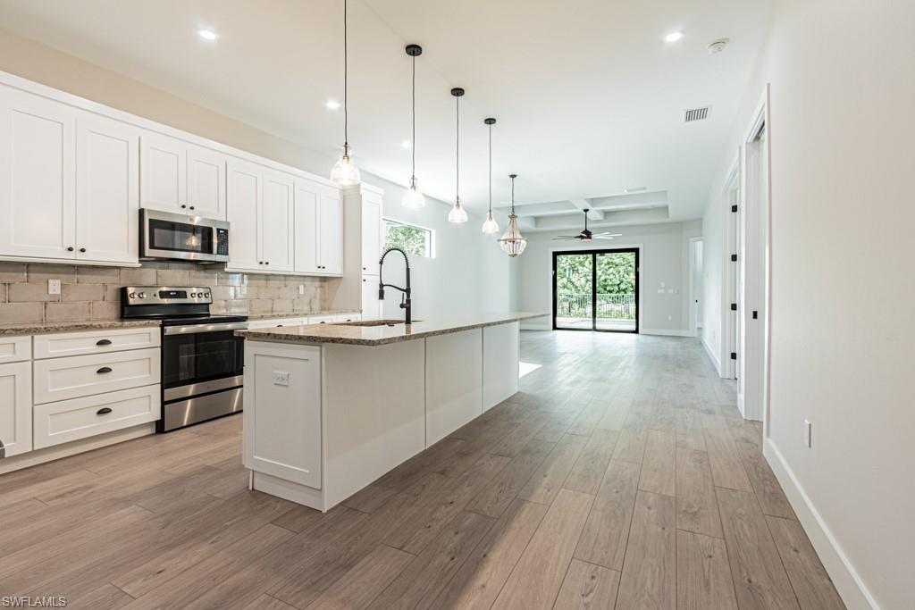 3552 Hibiscus Avenue Naples, FL 34104 - Photo 9 of 34 a large kitchen with stainless steel appliances granite countertop a stove a sink a refrigerator and white cabinets with wooden floor