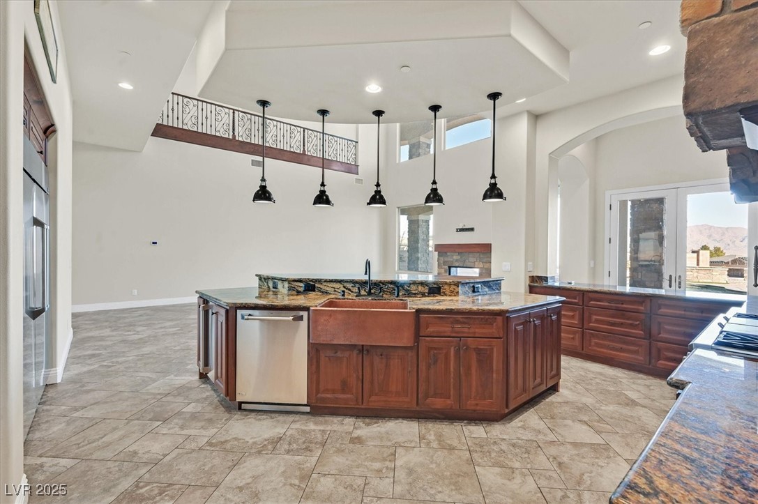 5790 Aspen Falls Circle Las Vegas, NV 89149 - Photo 11 of 61 Kitchen featuring plenty of natural light, arched walkways, dark stone counters, light stone finish floors, and a high ceiling