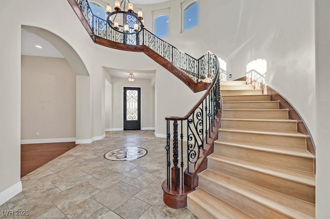 5790 Aspen Falls Circle Las Vegas, NV 89149 - Photo 3 of 61 Entrance foyer featuring a chandelier, stone tile flooring, arched walkways, stairway, and a high ceiling