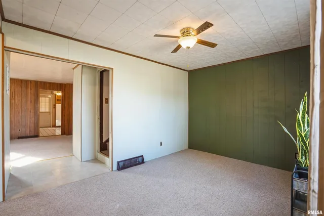 an empty room with a chandelier fan and windows
