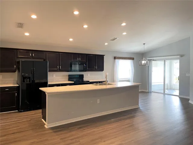 a view of kitchen with stainless steel appliances wooden floor sink stove and wooden floor