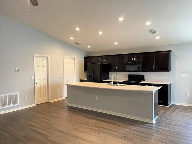 a living room with stainless steel appliances kitchen island granite countertop a stove and a refrigerator with wooden floor