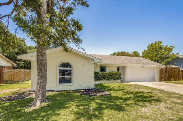 a view of a white house next to a yard with large trees