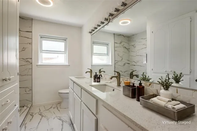 a bathroom with a granite countertop sink a large mirror and a toilet