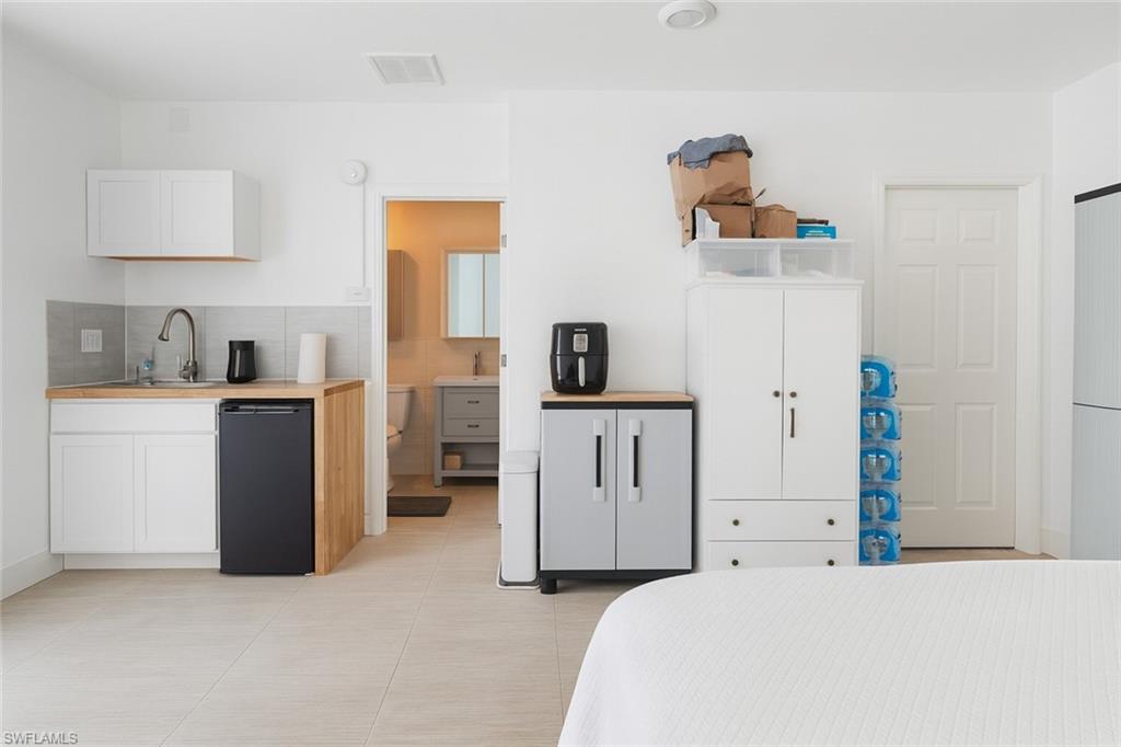 5010 31st Avenue Southwest Naples, FL 34116 - Photo 23 of 33 a bedroom with a bed and white cabinets