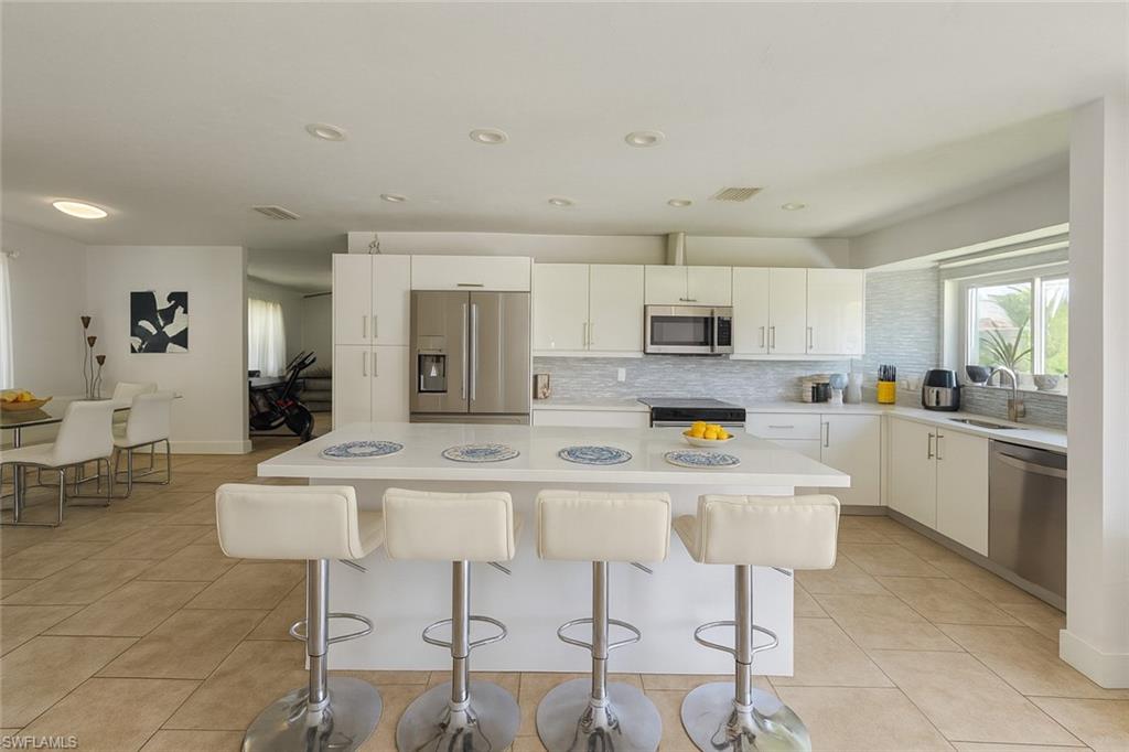 5010 31st Avenue Southwest Naples, FL 34116 - Photo 8 of 33 a kitchen with white cabinets and stainless steel appliances