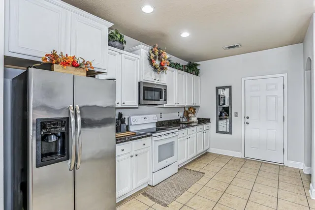 a kitchen with stainless steel appliances kitchen island granite countertop a refrigerator and a stove top oven