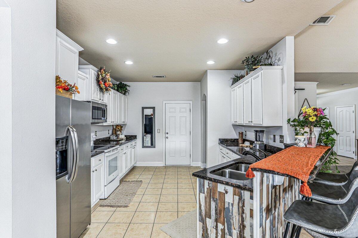 405 Pendo Place Crestview, FL 32536 - Photo 13 of 39 a kitchen with stainless steel appliances kitchen island granite countertop a refrigerator and a stove top oven