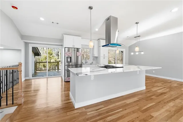 a large kitchen with kitchen island a stove a counter top space and wooden floor