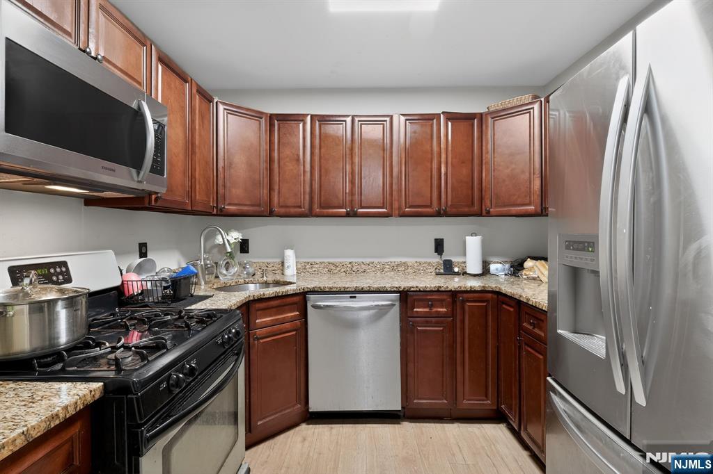 192 Burnett Avenue Maplewood, NJ 07040 - Photo 13 of 13 a kitchen with stainless steel appliances granite countertop a stove top oven a sink dishwasher and a refrigerator with wooden cabinets
