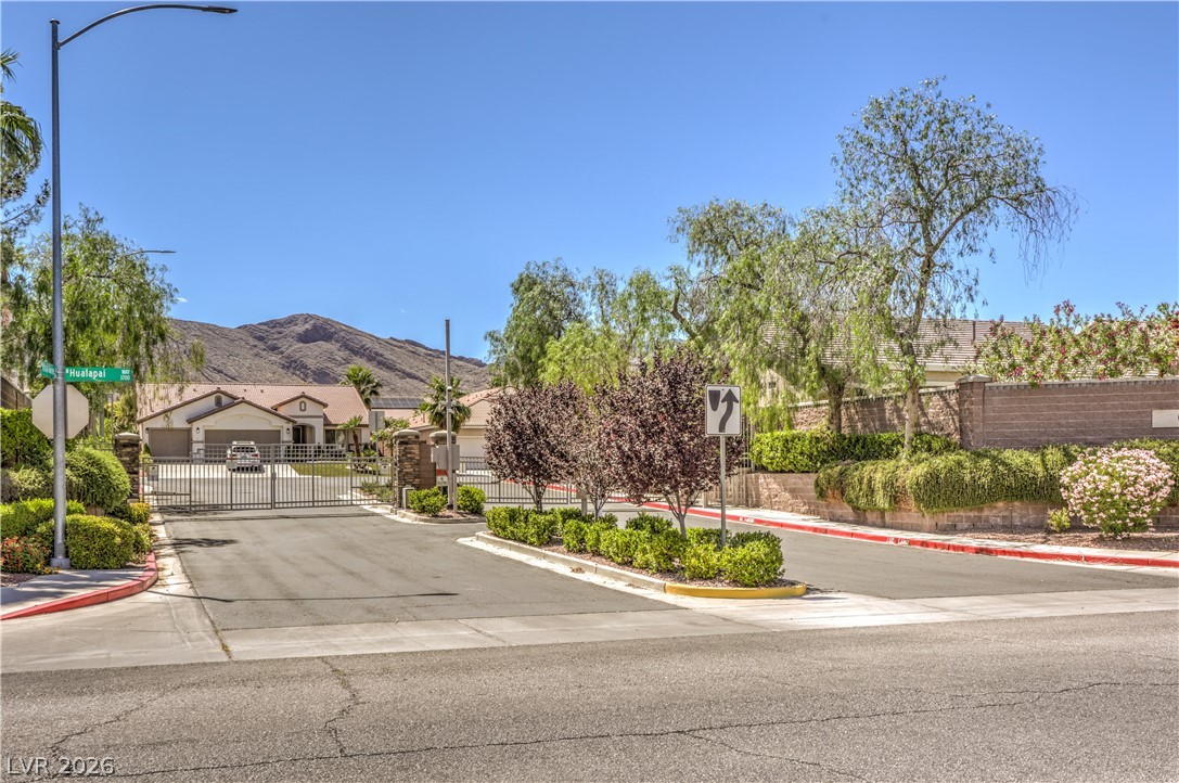 3713 Spring Shadow Road Las Vegas, NV 89129 - Photo 37 of 37 A private residential street leads to a gated community with desert landscaping and mountainous views.
