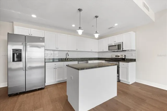 a kitchen with kitchen island white cabinets and stainless steel appliances