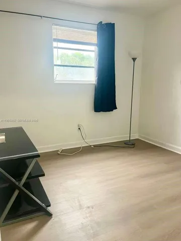 a view of a room with wooden floor and a window