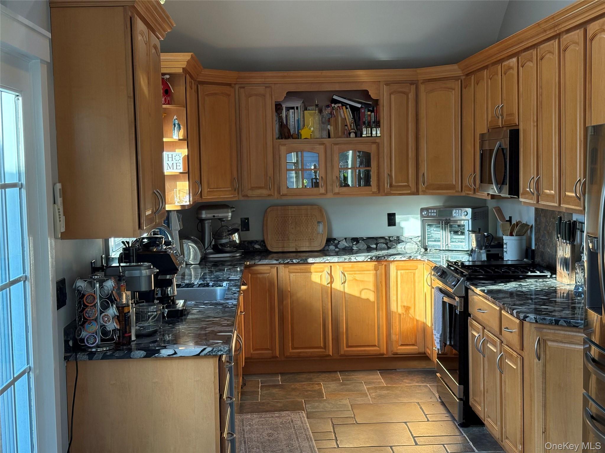 40 Alton Road Babylon, NY 11702 - Photo 18 of 41 Kitchen featuring stainless steel appliances, dark counters, brown cabinetry, and open shelves