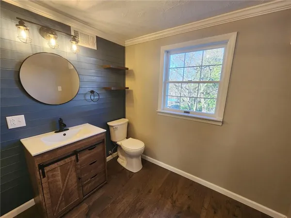 a bathroom with a toilet sink vanity and mirror