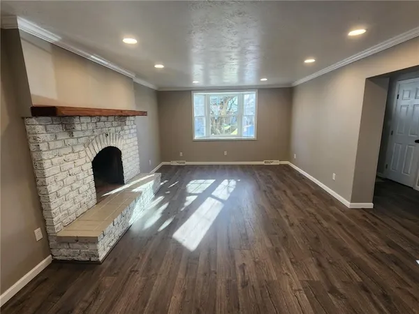 an empty room with wooden floor a fireplace and windows