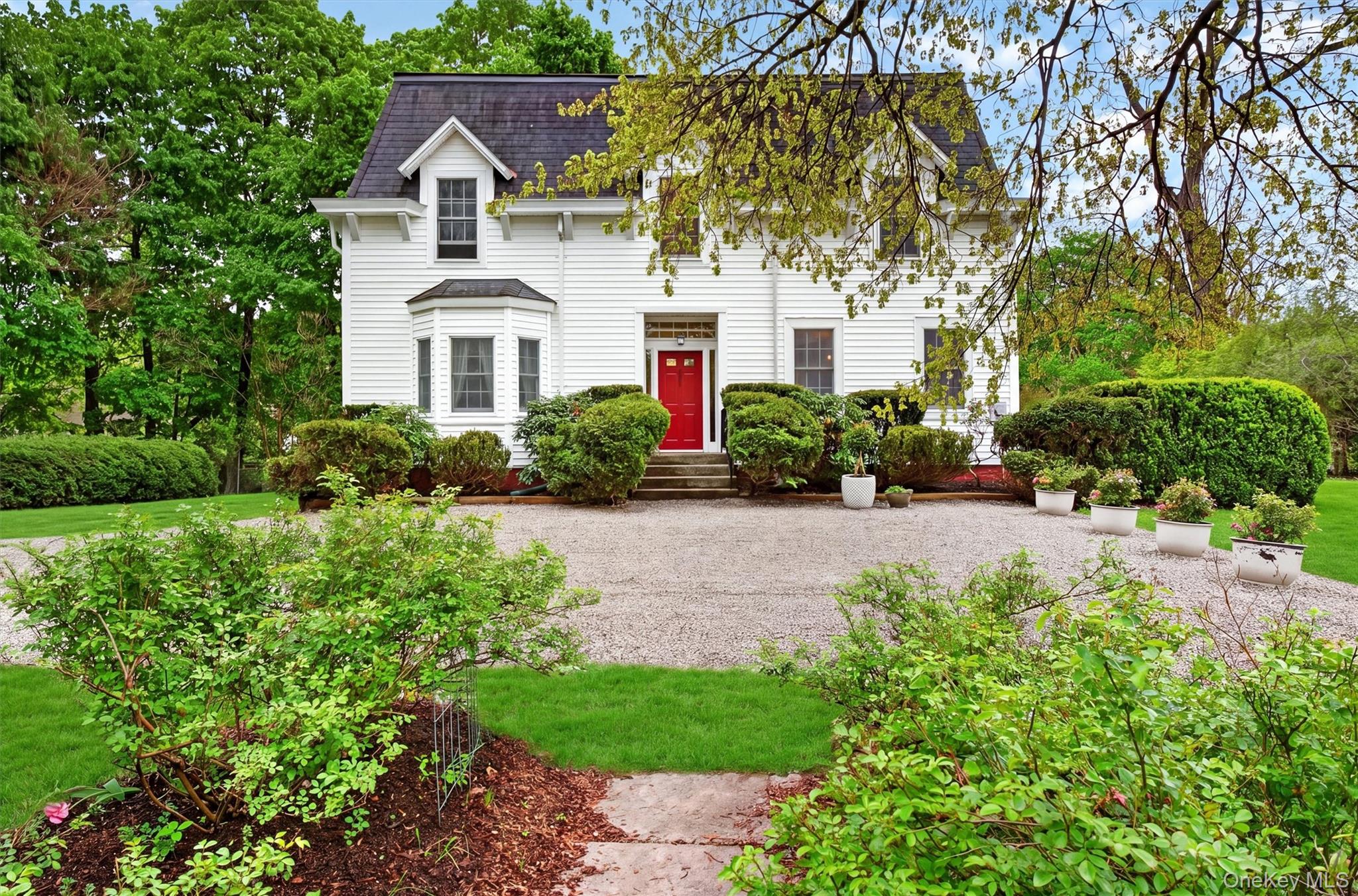 121 Old Glenham Road Fishkill, NY 12524 - Photo 1 of 50 Exterior of colonial residence with red door and mansard roof. Gravel driveway with manicured gardens surrounding.