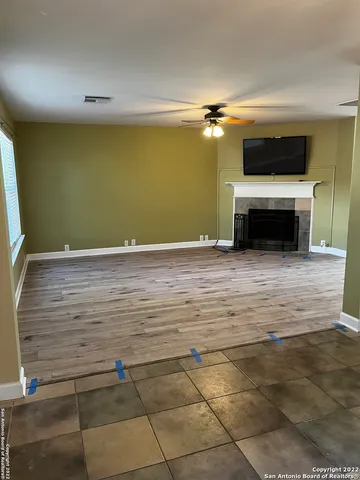a view of a livingroom with a fireplace a ceiling fan and wooden floor