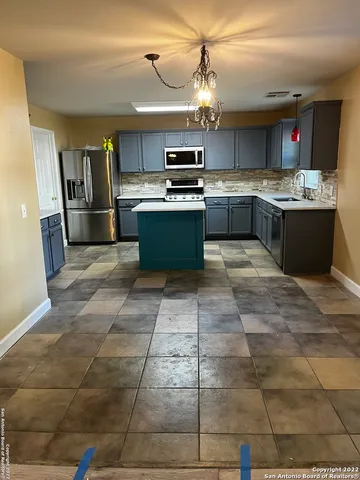 a large kitchen with granite countertop a stove a sink and a refrigerator