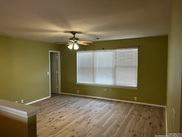an empty room with a windows and chandelier fan